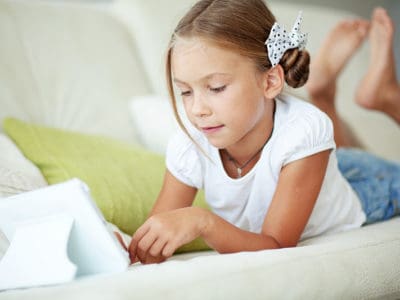 A young girl on an iPad during screentime at her home.
