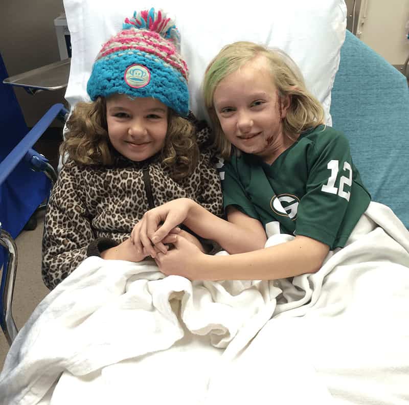 Two girls sitting in an ER hospital bed after a dog bite