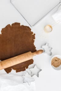 Gingerbread house recipe ingredients, a rolling pin, and gingerbread dough rolled out.