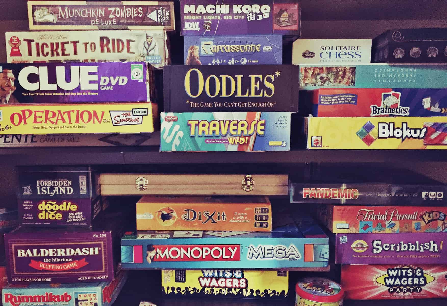 Stacked board games in a closet representing the best games for families!