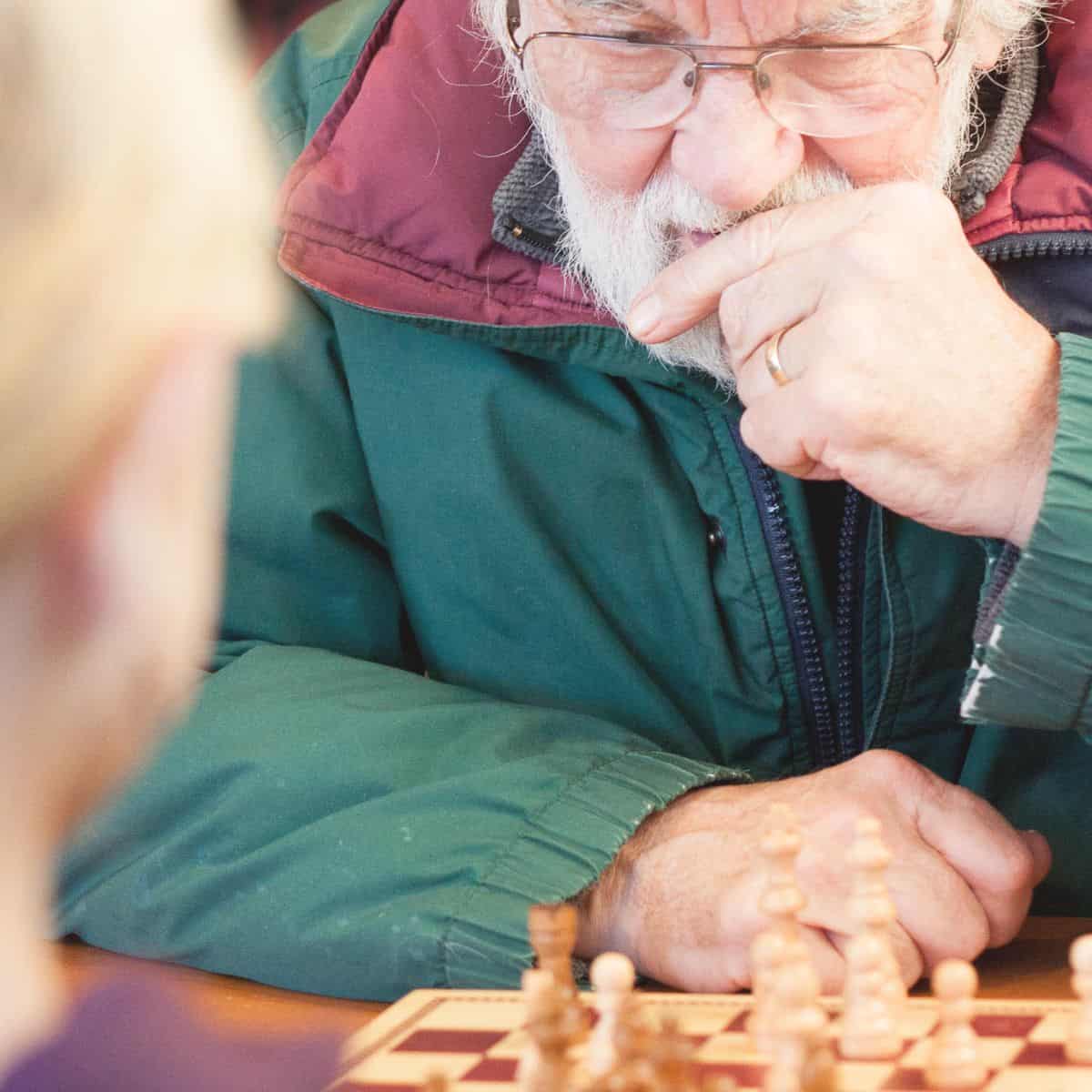 A grandparent playing a game with his granddaughter at a coffee shop.