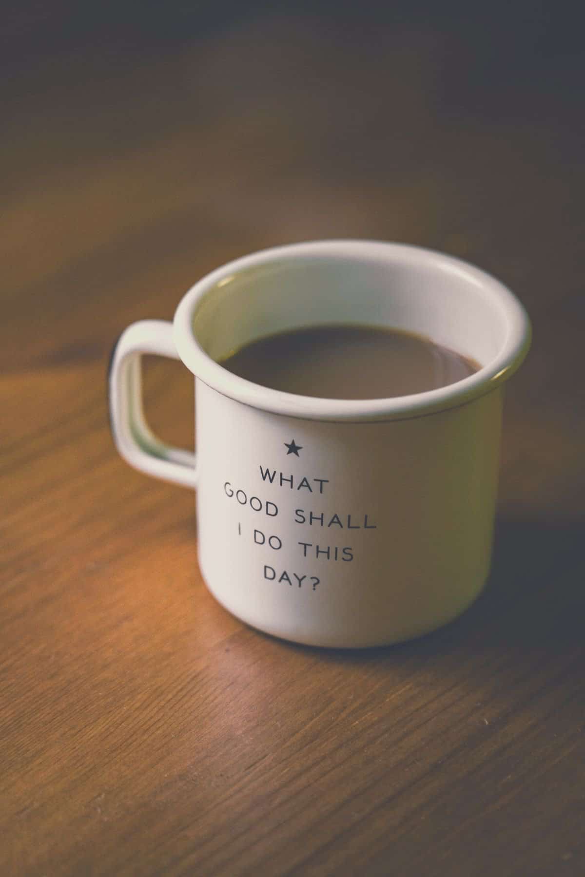 A full coffee cup that reads, "What good shall I do this day?"