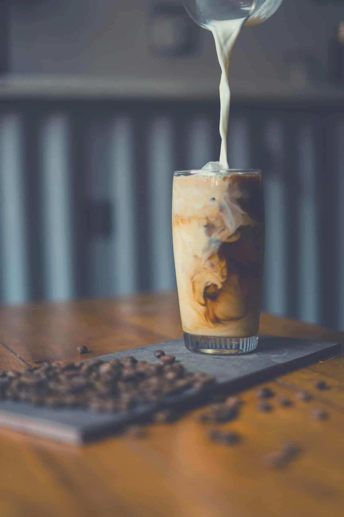 Cream being poured into an iced-coffee.