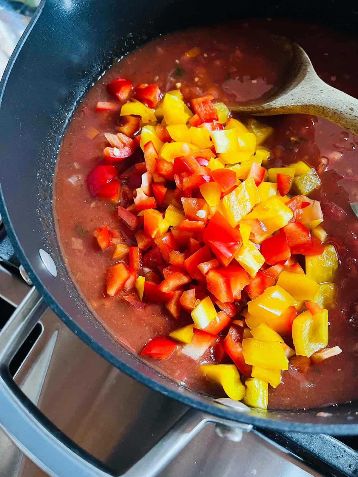 A pot of turkey taco soup with fresh bell peppers being stirred in.